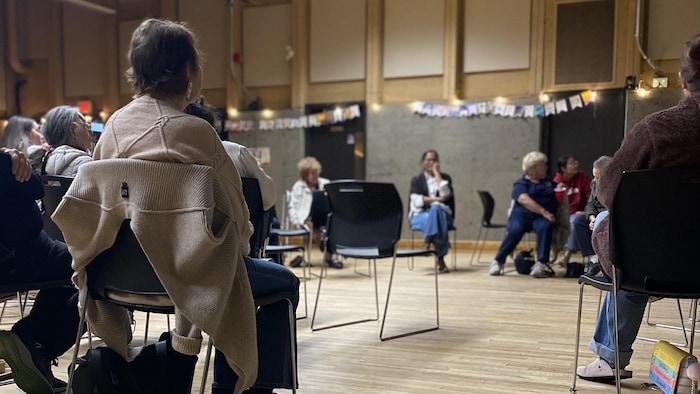 Des aînées assises dans un cercle de discussion dans une salle communautaire.