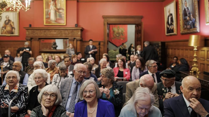 Des personnes sont assises dans une salle pour la remise de prix de reconnaissance pour aînés.
