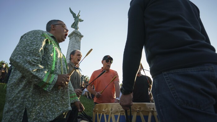 Des hommes frappent un tambour en chantant.