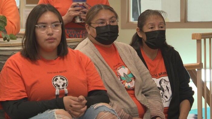 Tres mujeres llevan poleras naranja.