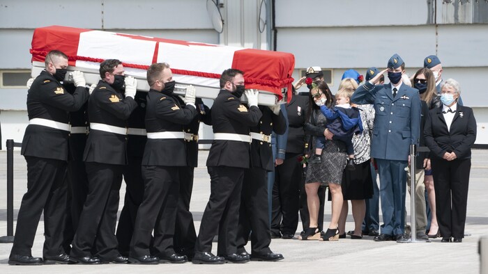 Des militaires arborant un masque portent le cercueil de l'enseigne de vaisseau de première classe Abbigail Cowbrough lors de la cérémonie à la mémoire des victimes de l'écrasement de l'hélicoptère CH-148 Cyclone.