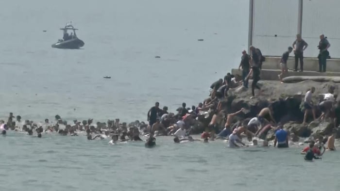Des migrants traversent à la nage la frontière à partir du Maroc et escaladent des rochers pour atteindre la barrière frontalière, à Ceuta, le 30 juillet 2026.