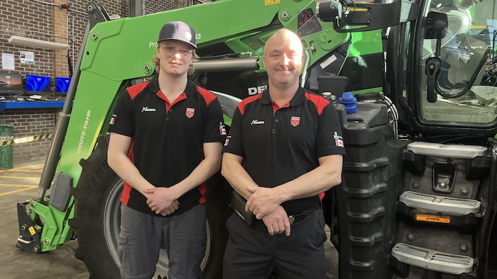 Luke Emeny et Marco Bisson posent pour la caméra devant un gros tracteur.