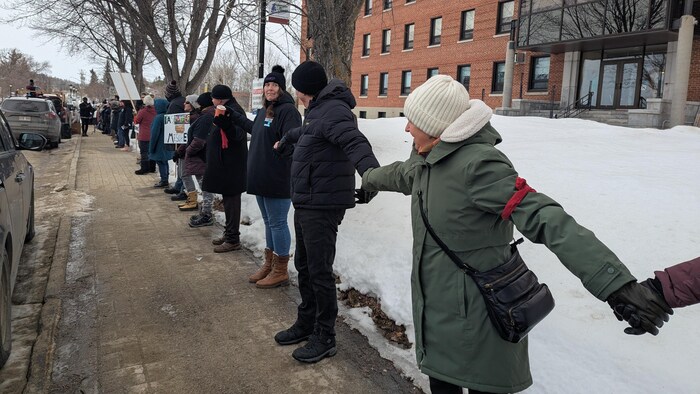 Des personnes se tiennent la main dans le but de faire une chaîne humaine devant l'hôpital de Ville-Marie.