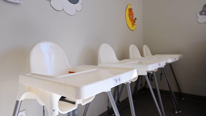 Trois chaises hautes pour bébés alignées contre un mur.