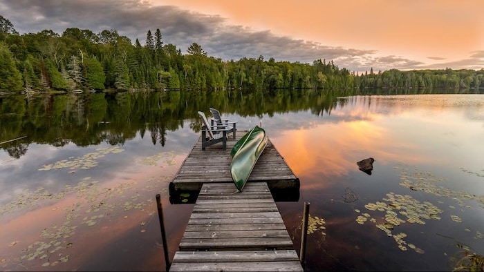 Un canot et des chaises au bout d'un quai au crépuscule dans la région de Haliburton Highlands, en Ontario.