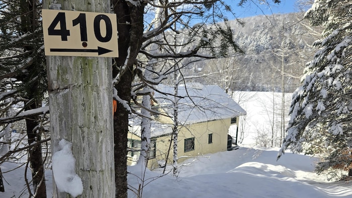 Un chalet situé sur le bord d’un lac, dans un milieu boisé, en hiver.