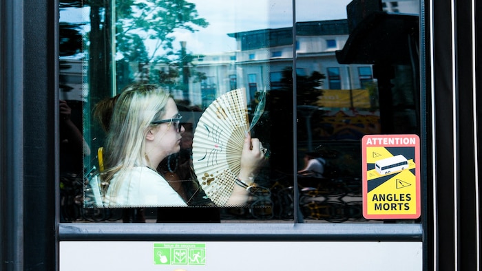 Une femme s'évente dans un bus.