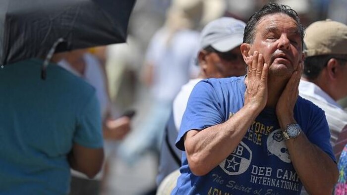 Un homme se rafraîchit à une fontaine publique le 30 juin 2019 sur la place Saint-Pierre au Vatican.