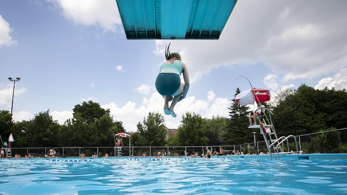 Une enfant saute dans une piscine publique.