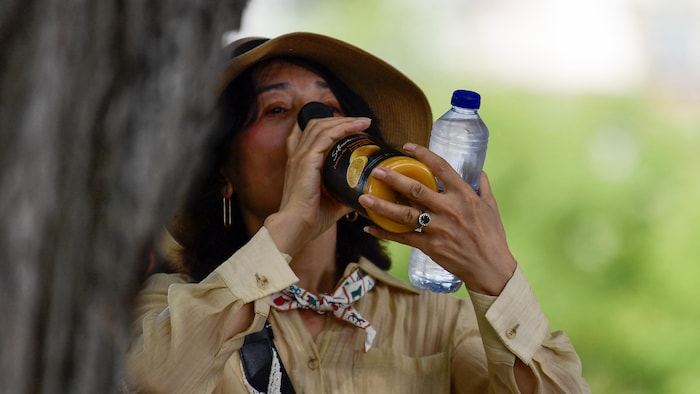 A woman drinks orange juice during the first summer wave of summer in Seville. heat waves southern europe: health