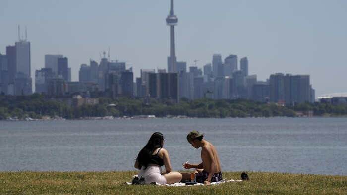 Un couple mange au bord du lac Ontario avec, en arrière-plan, le centre-ville de Toronto.