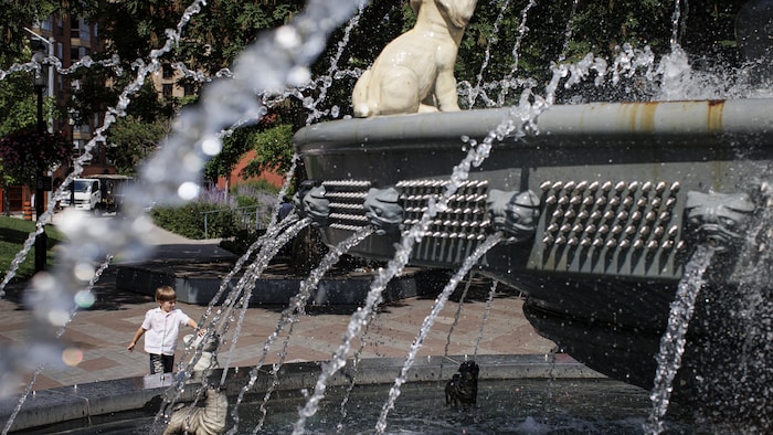 Un garçon joue dans une fontaine du centre-ville de Toronto.