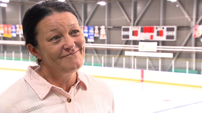 Elle donne une entrevue à l'orée d'une patinoire.