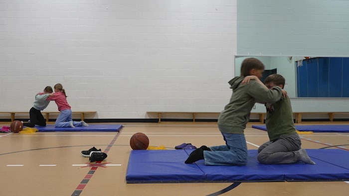 Des élèves luttent dans un gymnase.