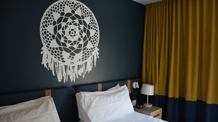 Deux lits simples un à côté de l'autre avec des décorations d'inspiration autochtone sur les mures