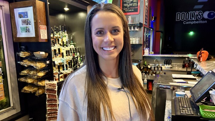 Franceska Lurette sourit à la caméra, derrière un comptoir-caisse.