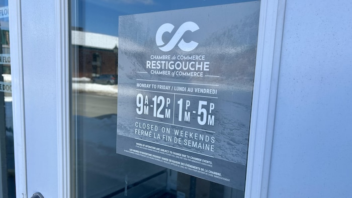 Une porte et une affiche indiquant les heures d'ouverture.