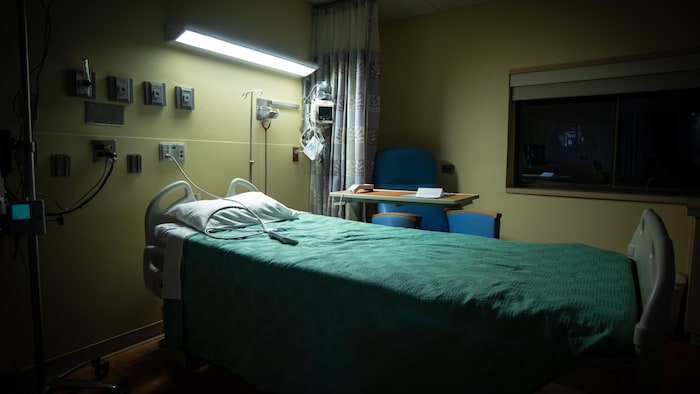 Un lit d'hôpital vide, la nuit.