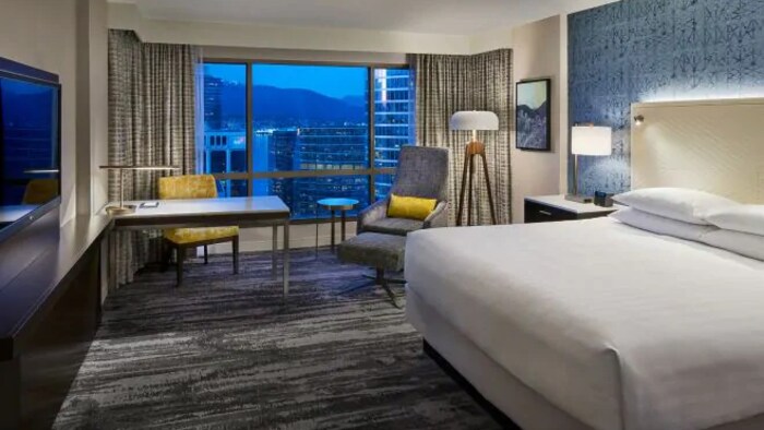 Une chambre à l'Hôtel Hyatt Regency de Vancouver avec un lit double, une télévision, une table et un fauteuil.