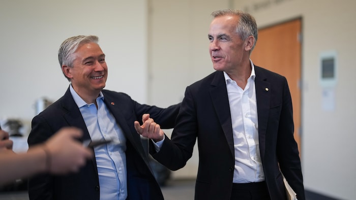 François-Philippe Champagne tient Mark Carney par les épaules. Les deux hommes sourient. 