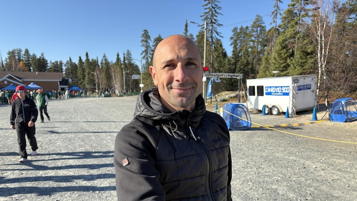 Un homme souriant à l'objectif, éloigné d'une foule.