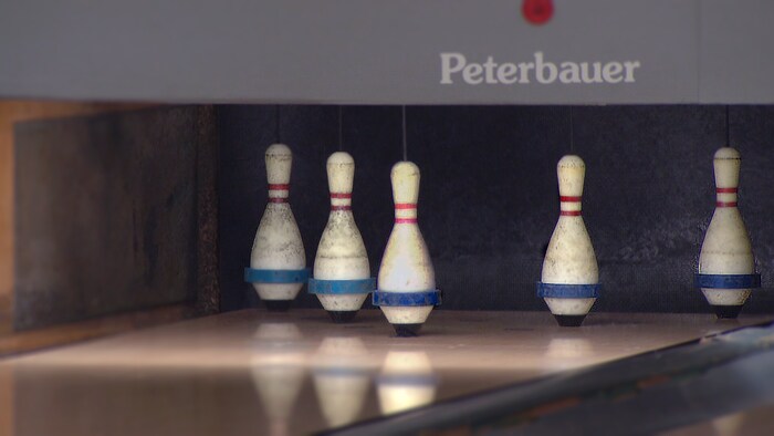Cinq quilles sont debout dans une allée de bowling.