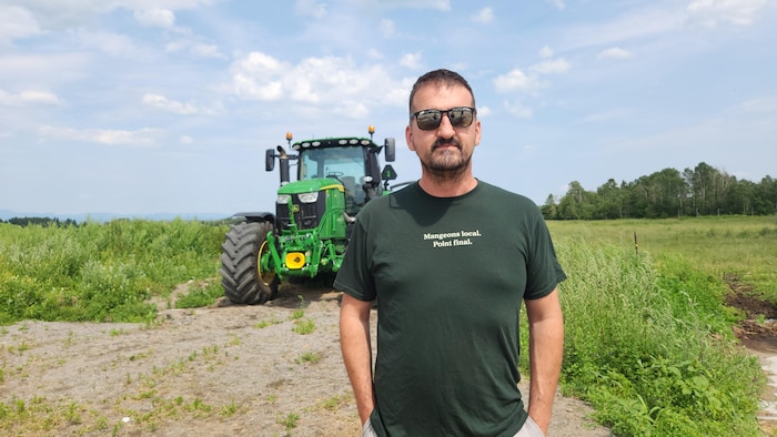 Un homme pose devant son tracteur.