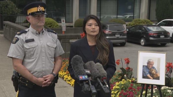 Deux policiers aux côtés d'une photo de la victime.