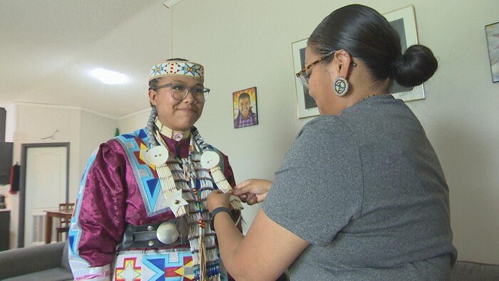 Une mère qui aide sa fille à ajuster un élément de son costume traditionnel crie.
