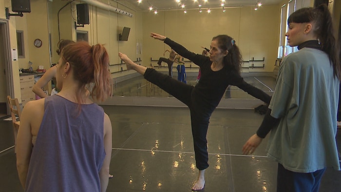Une danseuse professionnelle dans un studio danse devant deux autres danseuses.