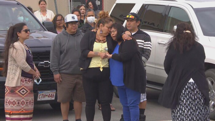 Plusieurs Autochtones de la famille en pleurs et attristés autour d'une voiture. 