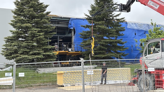 La structure d’un aréna en réparation est recouverte de bâches de protection.