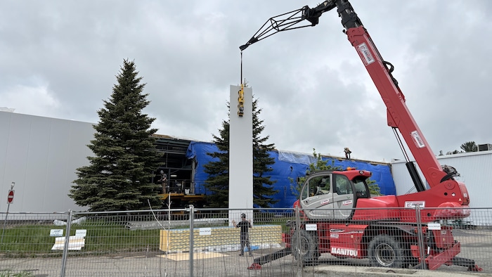 Un panneau de revêtement extérieur est suspendu au bout d’une grue.