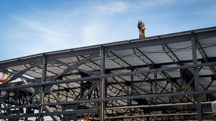Un travailleur effectue des travaux sur le toit d'une structure en acier.