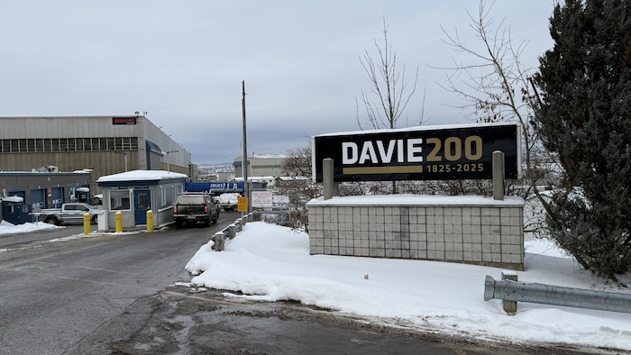 Une guerite avec des camions devant un chantier naval et la pancarte de la Davie.