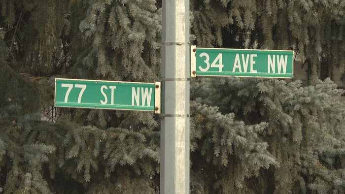 Gros plan sur un poteau métallique supportant deux plaques de rue indiquant l'intersection de la 77e rue N.-O. et de la 34e av. N.-O.