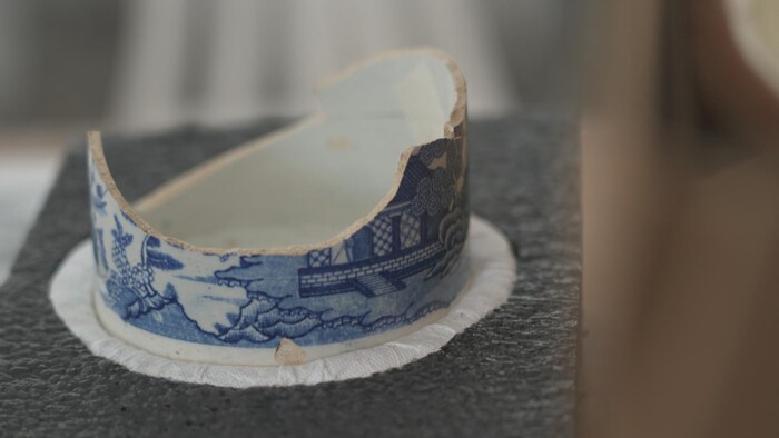 Une tasse en céramique, avec des peintures de couleur bleue, est fendue en deux.
