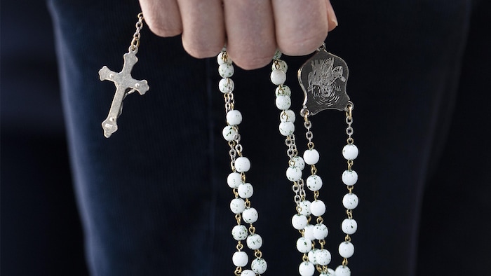 A person is holding a rosary.
