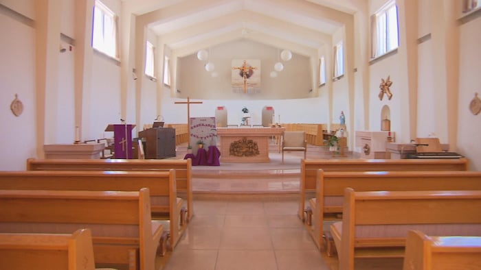 Des bancs d'église, un autel et des signes religieux.