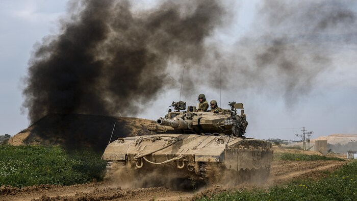 Un char israélien avance sur une route de terre battue.