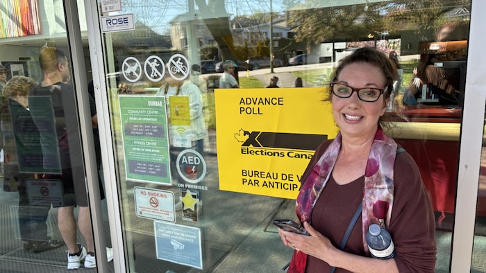 Une femme devant un bureau de vote.