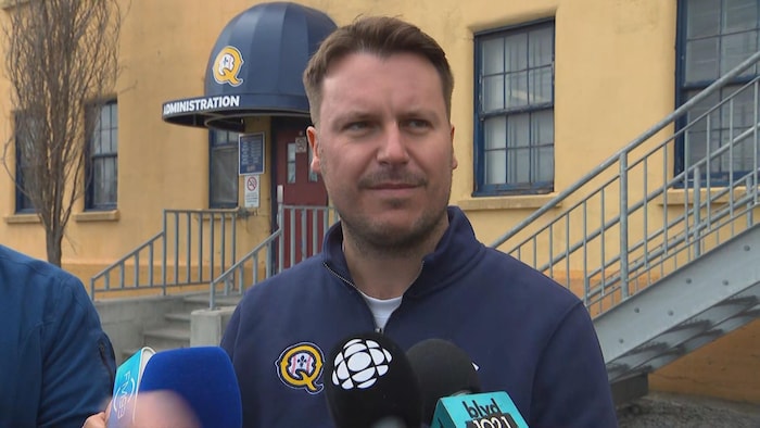 Un homme en point de presse devant un stade de baseball.