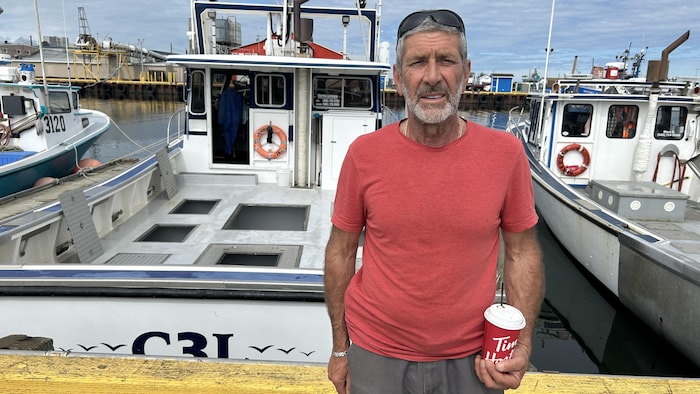 Charles Lanteigne devant un bateau de pêche au homard au quai de Caraquet.