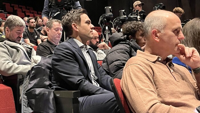 Charles Milliard assis dans une salle. 
