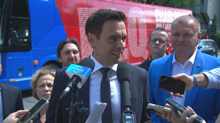Charles Milliard en point de presse devant son autocar, entouré de candidats.