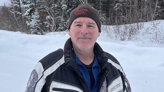 Charles Pinard porte une tuque et un manteau d'hiver. Il est dans un paysage sauvage hivernal.