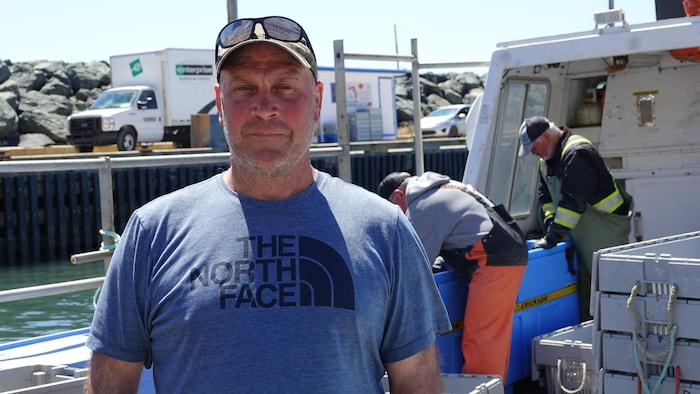 Charles Poirier photographié devant un bateau au quai de Pointe-Basse.