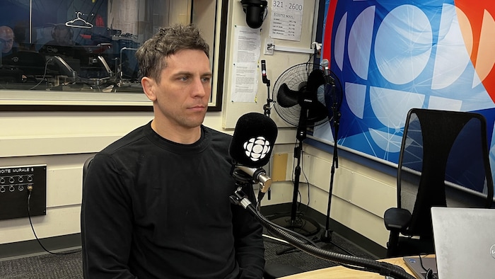 Un homme assis en studio pour une entrevue.