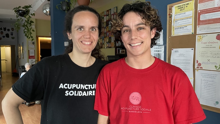 L'acupunctrice Charlotte Astier et l'acupuncteur Félix Dénommé. Les deux sourient. Ils portent des chandails sur lesquels les mots « acupuncture solidaire » et « acupuncture sociale » sont inscrits. 
